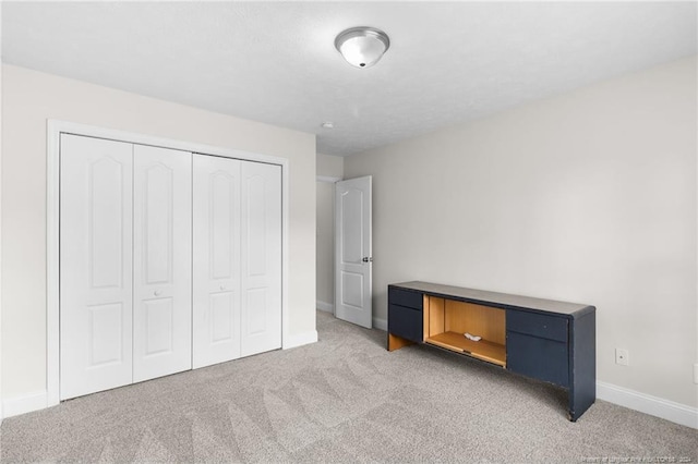 unfurnished bedroom with light colored carpet and a closet