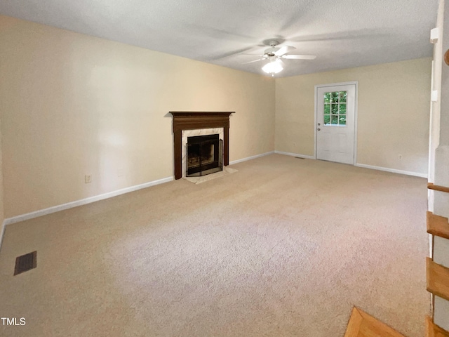 unfurnished living room featuring a high end fireplace, ceiling fan, and light colored carpet