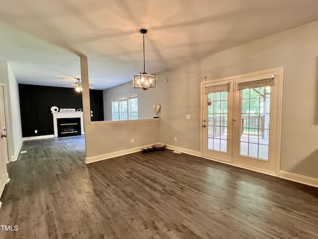 unfurnished dining area with ceiling fan with notable chandelier, dark hardwood / wood-style floors, and plenty of natural light