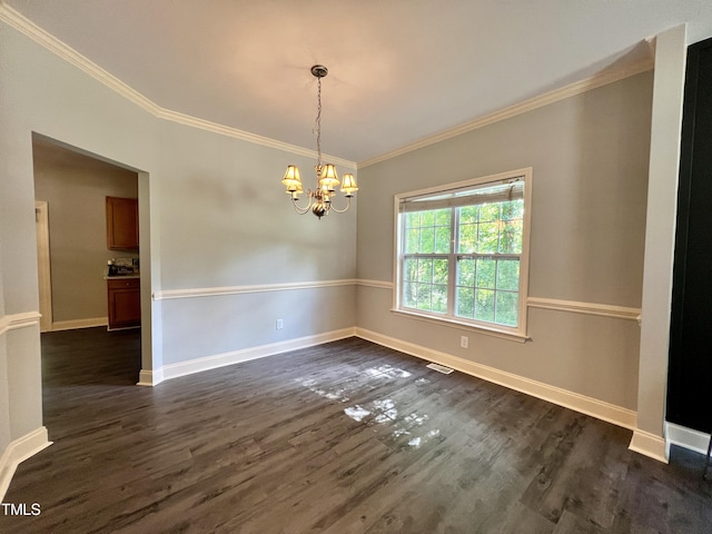 spare room with crown molding, dark wood-type flooring, and a notable chandelier