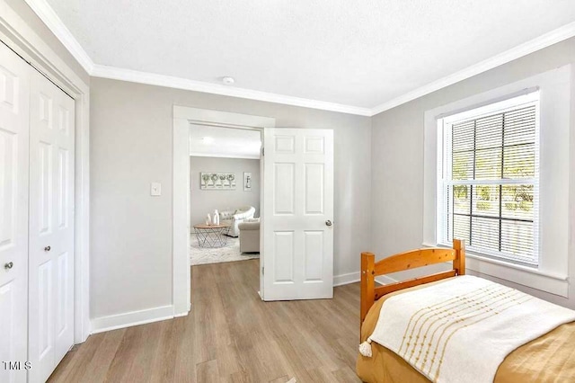 bedroom featuring crown molding, light wood-type flooring, and a closet