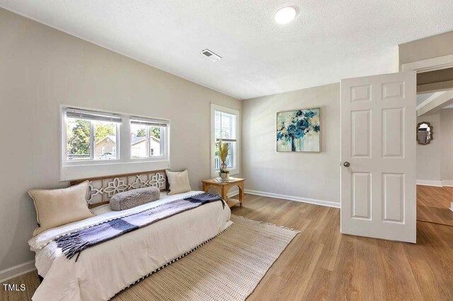 bedroom featuring a textured ceiling and light hardwood / wood-style floors