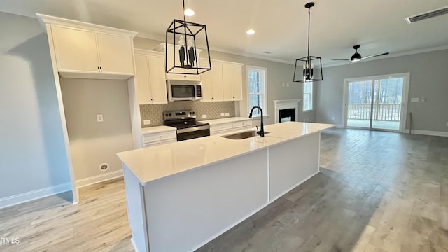 kitchen featuring a center island with sink, a healthy amount of sunlight, sink, and appliances with stainless steel finishes