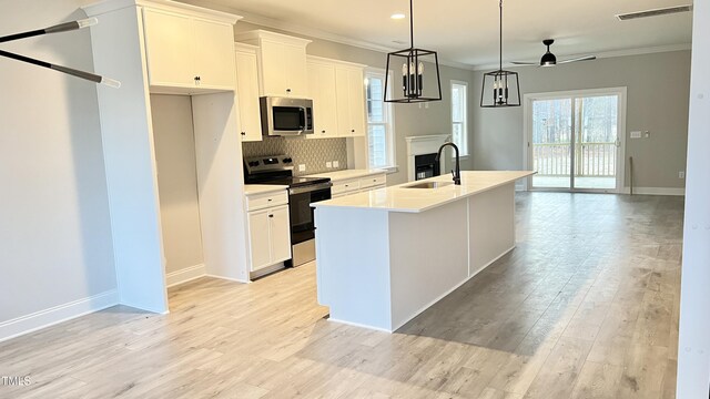 kitchen with white cabinetry, sink, ceiling fan, stainless steel appliances, and an island with sink