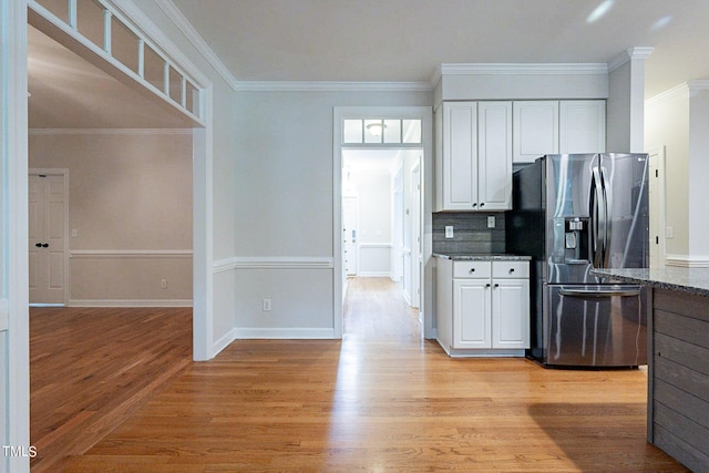 kitchen with light hardwood / wood-style flooring, white cabinets, stainless steel fridge with ice dispenser, dark stone counters, and ornamental molding