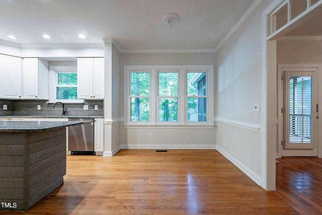 kitchen with white cabinets, dishwasher, tasteful backsplash, dark stone countertops, and crown molding