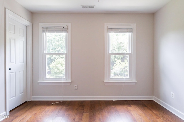 empty room with a healthy amount of sunlight and dark hardwood / wood-style flooring