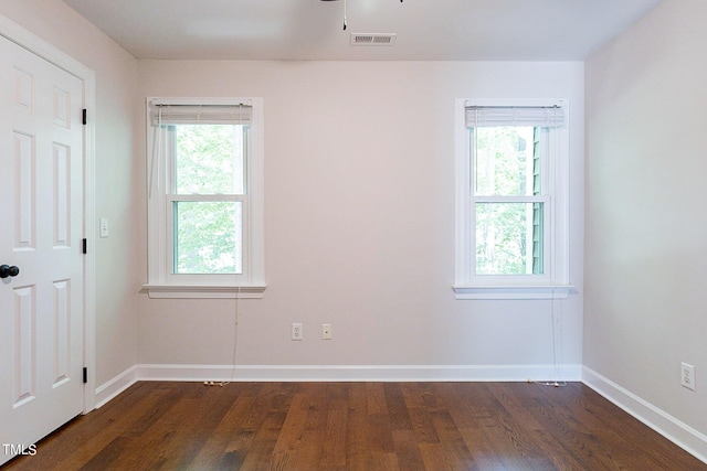 empty room featuring a healthy amount of sunlight and dark hardwood / wood-style floors