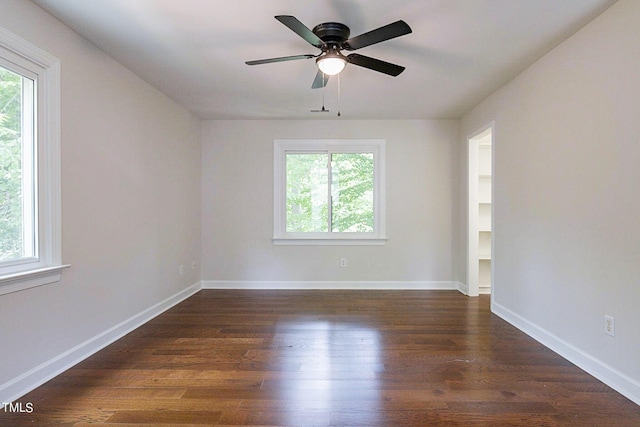 spare room with ceiling fan, a wealth of natural light, and dark wood-type flooring