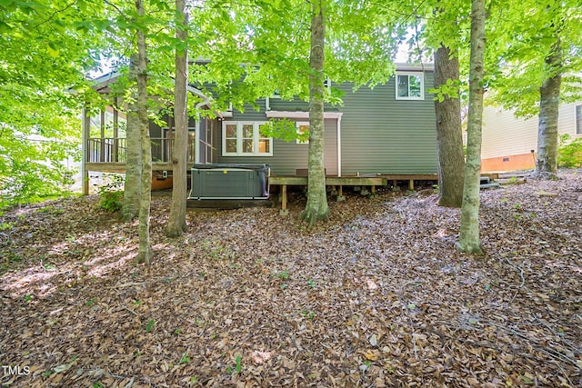 rear view of house with cooling unit, a sunroom, and a hot tub