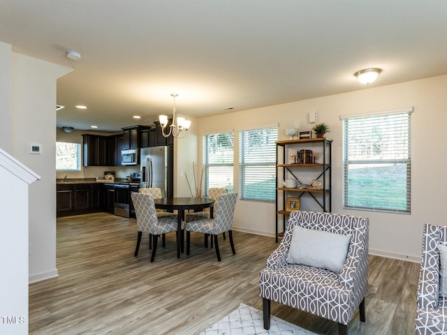 dining space with an inviting chandelier and light hardwood / wood-style flooring