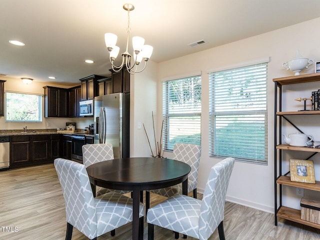 dining room with an inviting chandelier, light hardwood / wood-style flooring, and sink