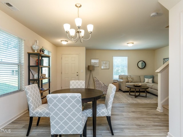 dining area with light hardwood / wood-style flooring and a chandelier