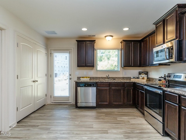 kitchen featuring light stone counters, a wealth of natural light, appliances with stainless steel finishes, and light hardwood / wood-style flooring