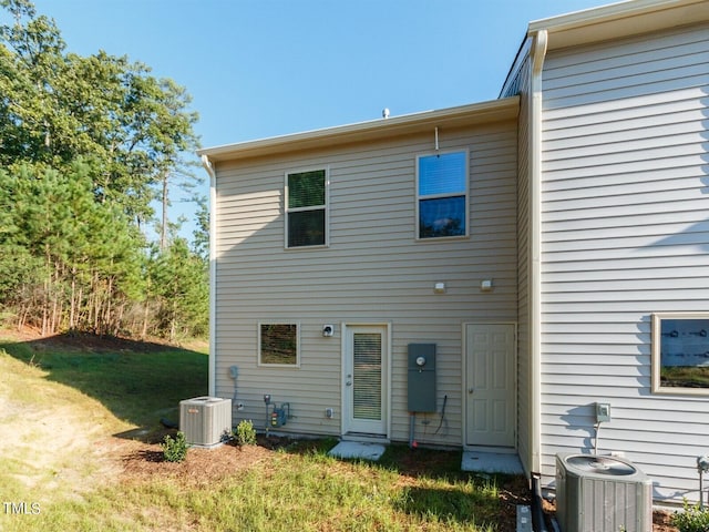 back of house featuring central AC unit and a lawn