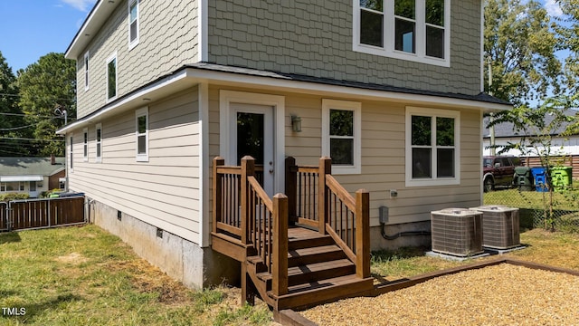 view of exterior entry with central AC unit and a lawn