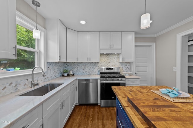 kitchen featuring stainless steel appliances, white cabinets, butcher block countertops, and decorative light fixtures