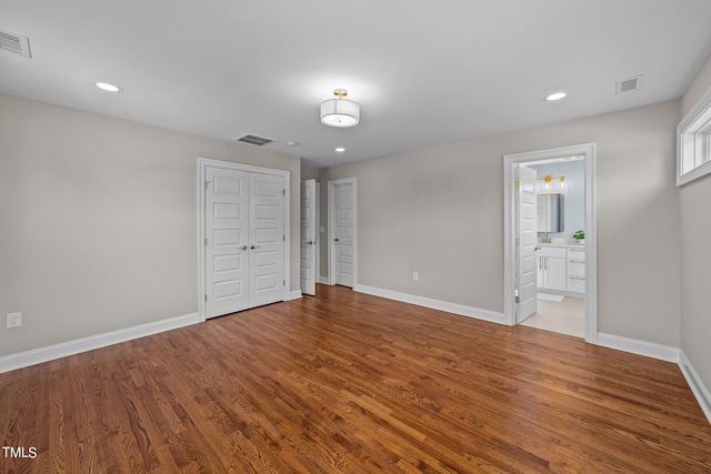 unfurnished bedroom with light wood-type flooring and ensuite bathroom