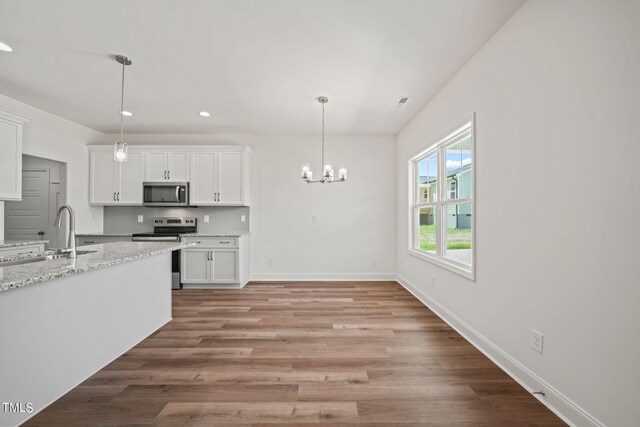 kitchen with appliances with stainless steel finishes, white cabinetry, decorative backsplash, sink, and light stone counters