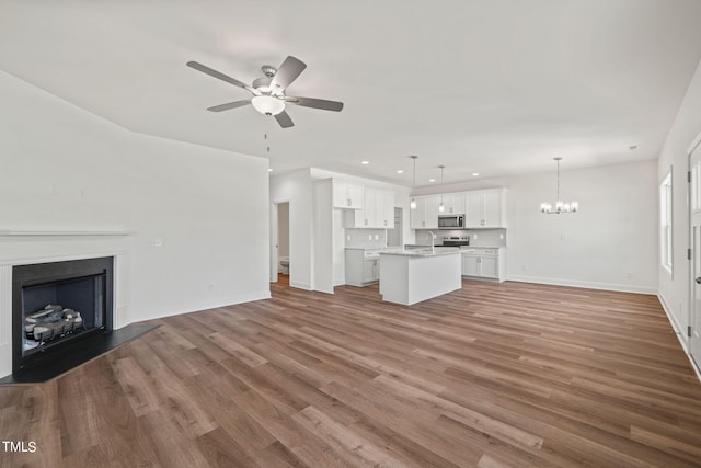 unfurnished living room featuring dark hardwood / wood-style floors, sink, and ceiling fan with notable chandelier