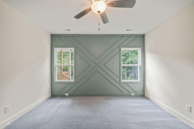 spare room with ceiling fan, a wealth of natural light, and light colored carpet