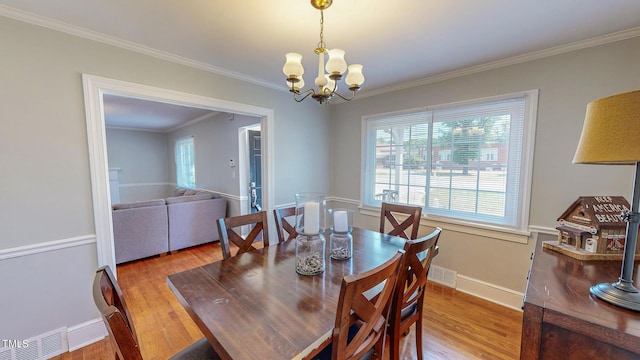 dining area featuring hardwood / wood-style floors, crown molding, and an inviting chandelier