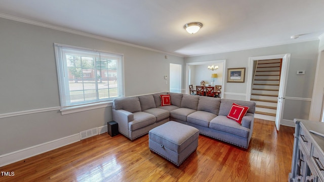 living room featuring wood-type flooring, a notable chandelier, and crown molding