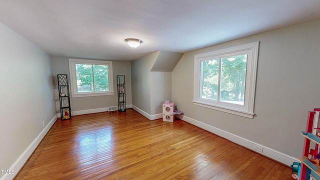 bonus room with vaulted ceiling, light hardwood / wood-style flooring, and a healthy amount of sunlight