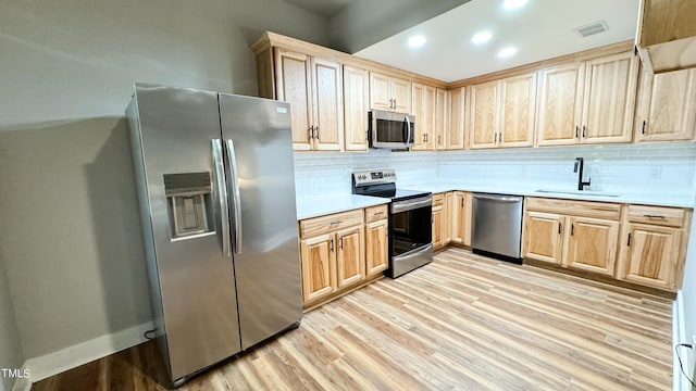 kitchen with tasteful backsplash, sink, light hardwood / wood-style flooring, and stainless steel appliances