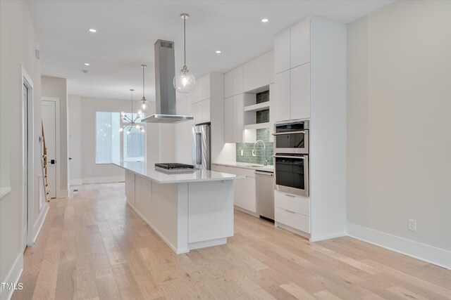 kitchen featuring light hardwood / wood-style flooring, stainless steel appliances, a notable chandelier, white cabinetry, and a kitchen island