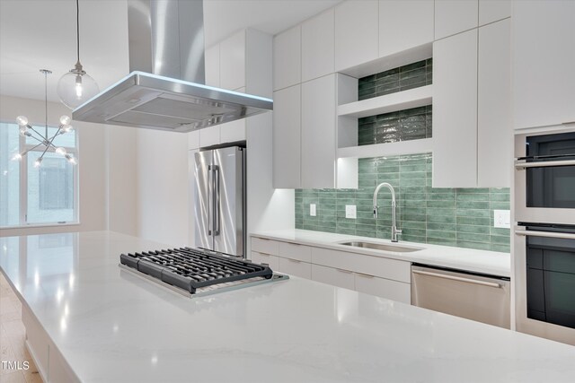 kitchen with backsplash, an inviting chandelier, stainless steel appliances, sink, and island range hood