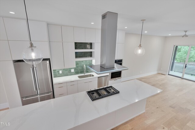 kitchen featuring pendant lighting, tasteful backsplash, stainless steel appliances, sink, and white cabinets