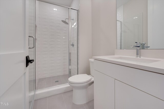 bathroom with tile patterned flooring, toilet, a shower with door, and vanity