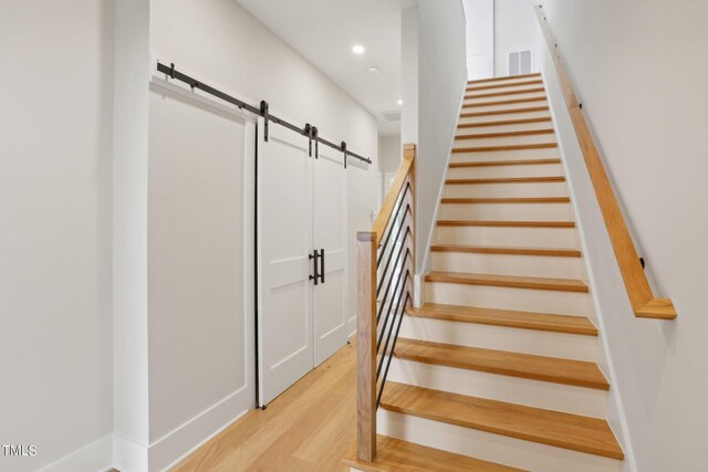 stairway featuring a barn door and hardwood / wood-style flooring