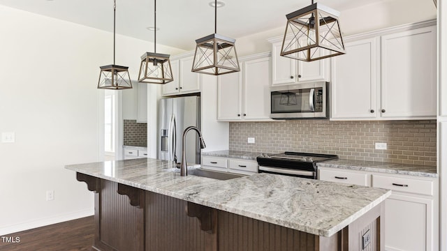 kitchen featuring a center island with sink, sink, stainless steel appliances, and hanging light fixtures