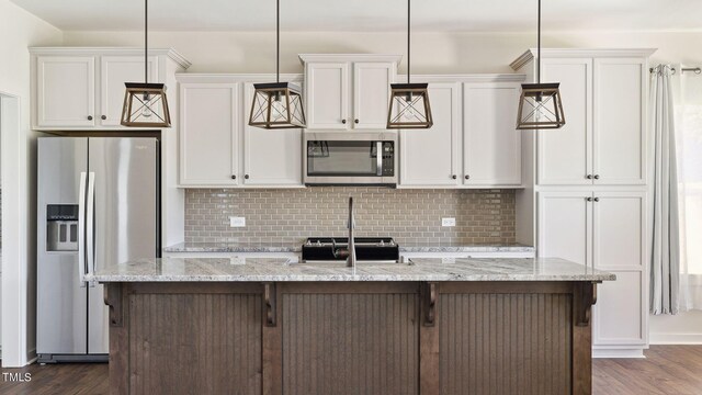 kitchen featuring a center island with sink, white cabinetry, hanging light fixtures, and appliances with stainless steel finishes