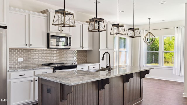 kitchen featuring a kitchen bar, appliances with stainless steel finishes, decorative light fixtures, and sink