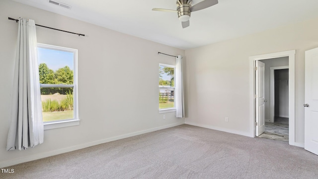 unfurnished bedroom featuring a walk in closet, ceiling fan, and light colored carpet