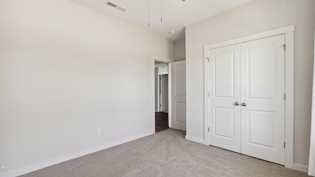 unfurnished bedroom with a closet and light colored carpet