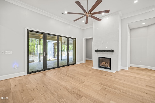 unfurnished living room featuring ornamental molding, a large fireplace, light hardwood / wood-style floors, and ceiling fan