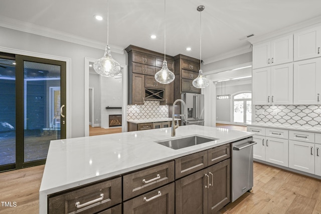 kitchen with decorative backsplash, light hardwood / wood-style floors, an island with sink, white cabinets, and decorative light fixtures