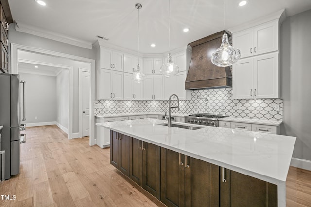 kitchen featuring hanging light fixtures, stainless steel fridge, white cabinets, custom exhaust hood, and light hardwood / wood-style flooring