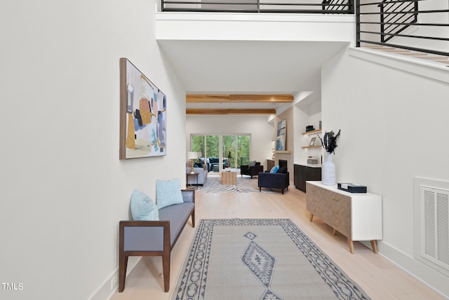 corridor featuring beamed ceiling, hardwood / wood-style flooring, and a towering ceiling