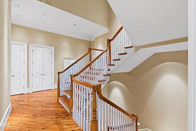 stairs featuring hardwood / wood-style floors, a towering ceiling, and ornamental molding