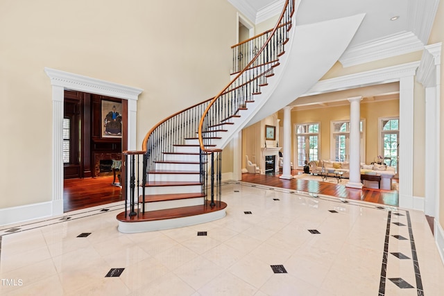 tiled entrance foyer featuring crown molding and decorative columns