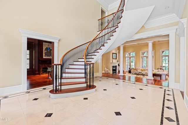 1820 Oatlands Ct, Wake Forest, NC 27587 - tiled entryway featuring a fireplace, ornate columns, ornamental molding, stairs, and a high ceiling