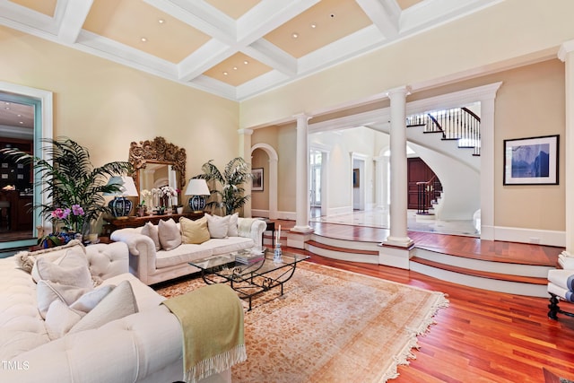 living room featuring coffered ceiling, hardwood / wood-style flooring, ornate columns, ornamental molding, and beamed ceiling