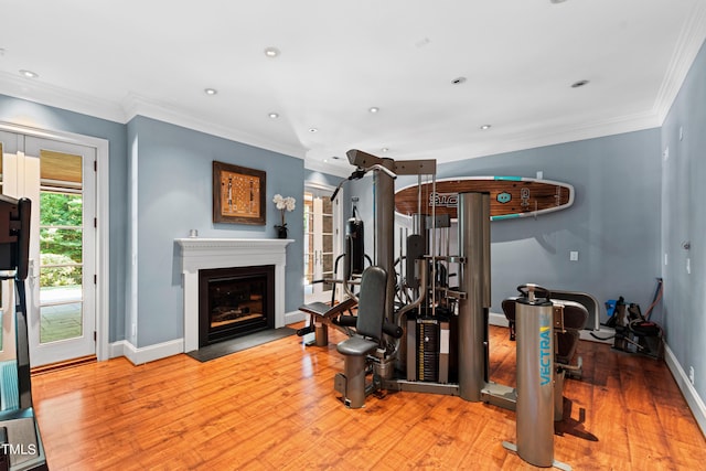 workout area featuring ornamental molding and light wood-type flooring