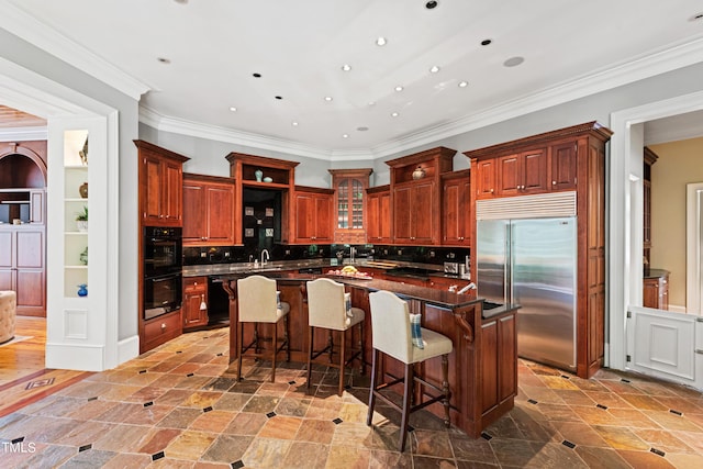 kitchen featuring black appliances, a breakfast bar, a center island, and crown molding