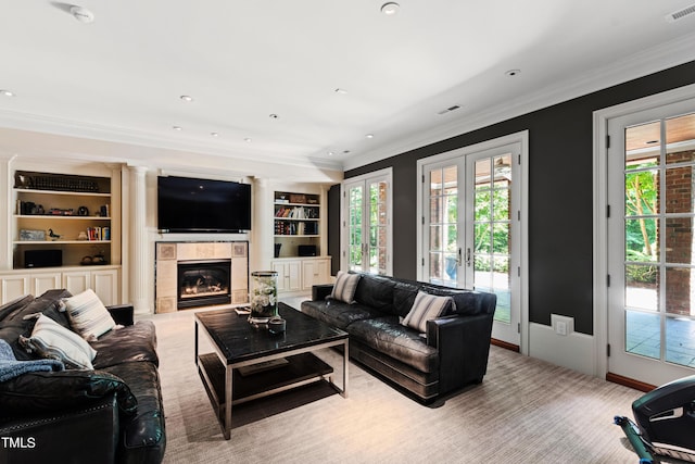 living room with french doors, ornamental molding, built in shelves, and a tiled fireplace